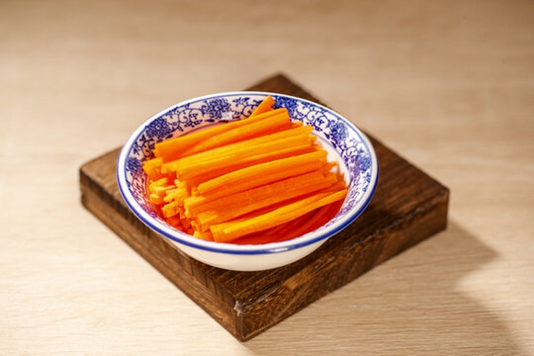 家庭厨房中正在制作红皮萝卜胡萝卜凉拌菜的过程场景