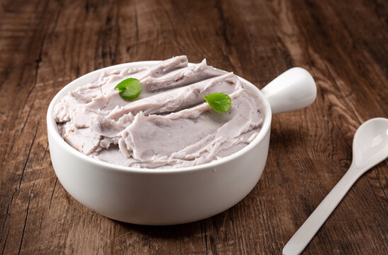 一张深色木质餐桌上摆放着一盏青花瓷小碗,碗中盛满细腻的灰紫色芋泥,表面撒有少许桂花和椰蓉,旁边搭配一把银色小勺,背景虚化,营造出温馨雅致的传统中式饮食氛围 传统中式甜品摆盘图