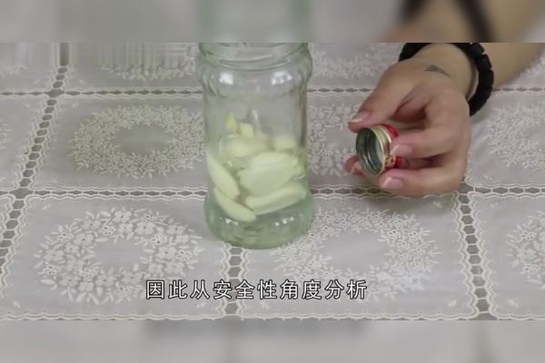 一位厨师戴着一次性手套,正在将揉软的蒜苔段压入透明玻璃广口瓶中,瓶身标签写着‘腌蒜苔’,桌上摆放着盐罐、辣椒和花椒,背景整洁明亮 装瓶密封过程