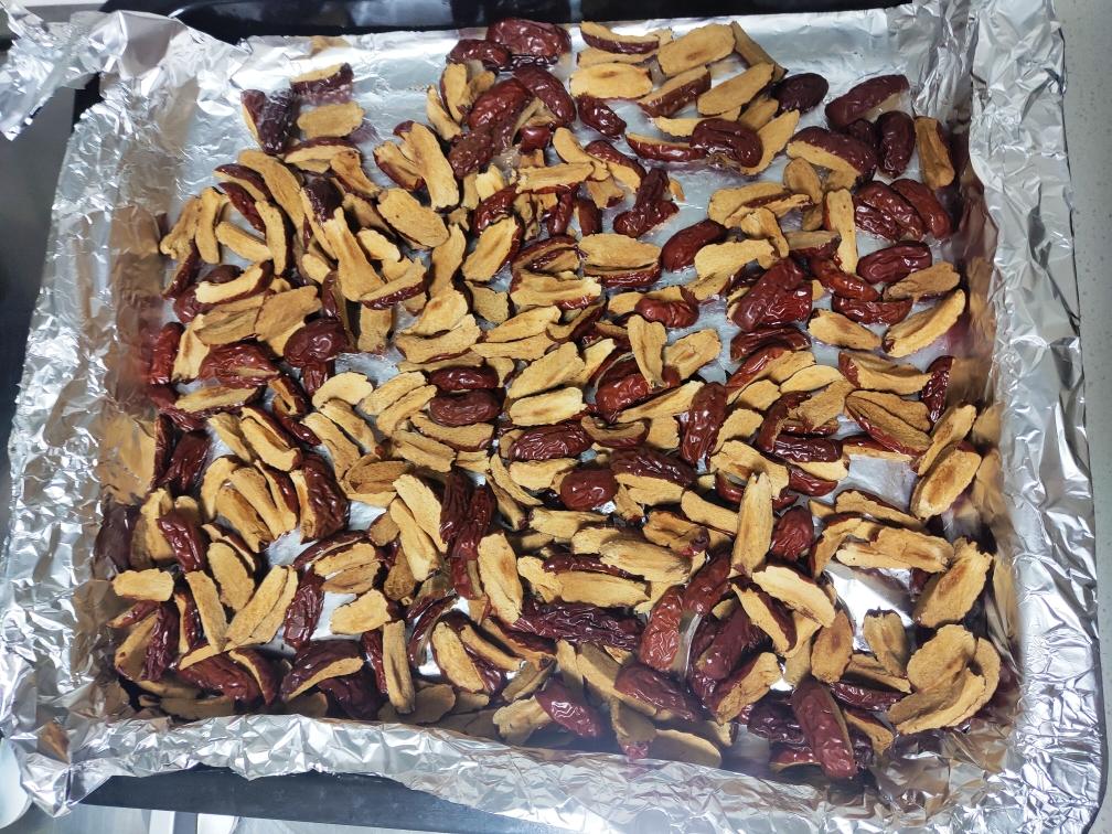 展示青枣被切片后放置在烤盘上,准备进行烘干处理,背景为厨房环境 青枣加工保存示意图