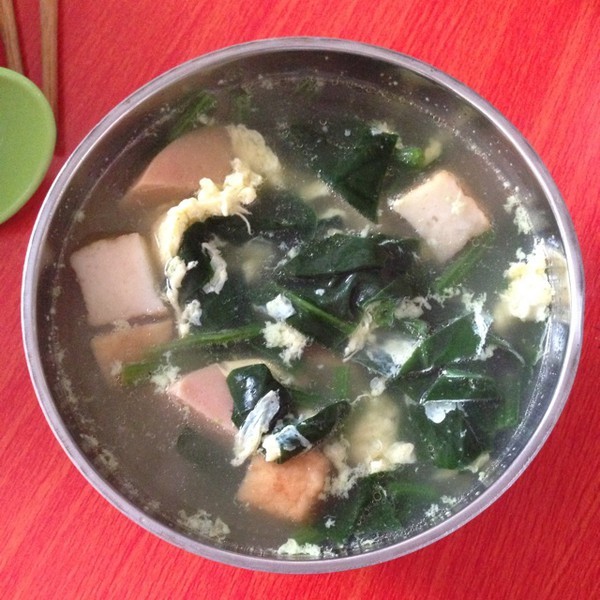 一碗热气腾腾的菠菜白萝卜汤,旁边摆放着新鲜食材 菠菜萝卜汤成品图