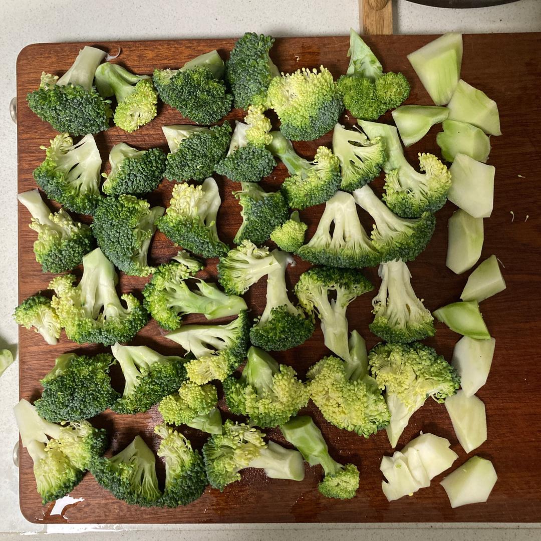 白花菜花被切块后置于木质砧板上,旁边有橄榄油、大蒜和香料,准备进行烹饪 白花菜花烹饪场景