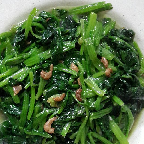 一道刚出锅的清炒菠菜海米,盛放在白色瓷盘中,菠菜翠绿鲜亮,海米呈淡橙红色,散落其间,表面略有油光,旁边配有木筷一双,背景虚化,突出菜品色泽与家常感 菠菜炒海米成品菜肴