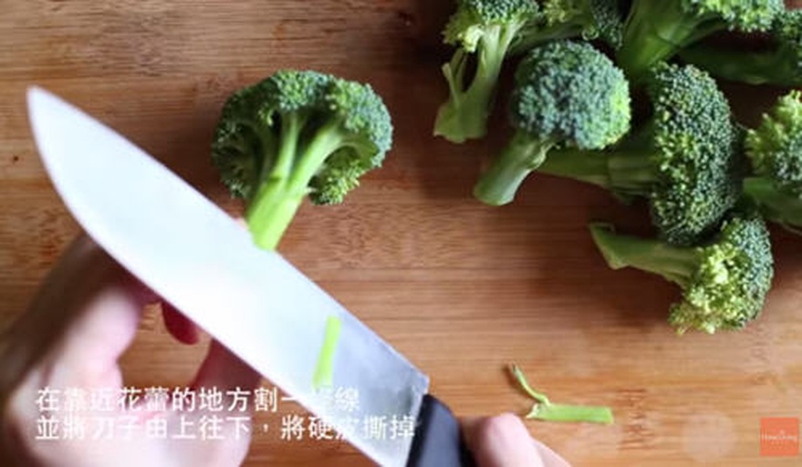厨房操作台上摆放一颗新鲜西兰花,旁边有厨师正在用刀将其顶部花簇与主茎分离;第二步展示如何用削皮刀去除茎部粗糙外皮;第三步显示已处理好的花蕾小朵和切成薄片的嫩茎,整齐排列在白色瓷盘中,背景为木质砧板和不锈钢水槽 西兰花切割过程演示图