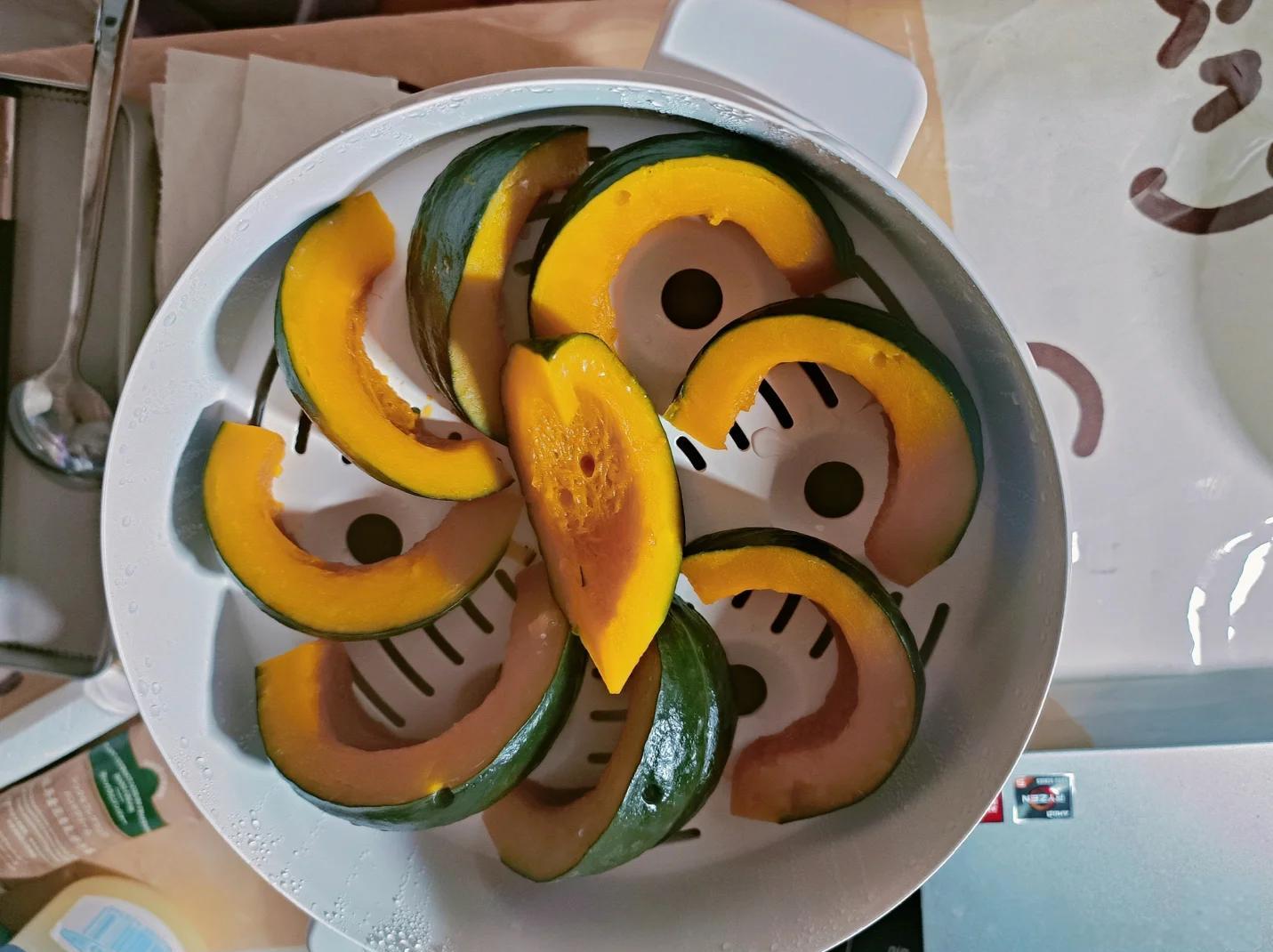 一位中老年人正在厨房用蒸锅烹饪南瓜片
