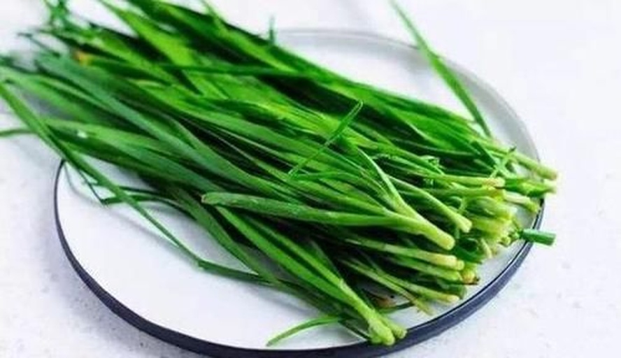 新鲜翠绿的韭菜整齐摆放在左侧,右侧为一瓶市售品牌蚝油,标签清晰可见,背景为厨房操作台面,光线自然明亮 韭菜与蚝油实物对比图