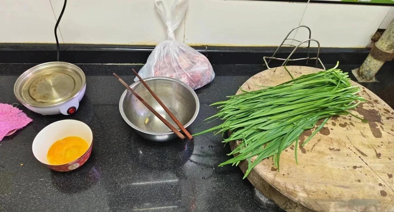 厨房台面上摆放着两枚新鲜鸡蛋、一小碟红色北五味子干果、一个玻璃量杯装有温水、一个小碗内是已泡发并捣碎的北五味子,旁边配有盐罐和研钵,背景为木质砧板,整体呈现自然健康的烹饪氛围 五味子蒸蛋食材展示