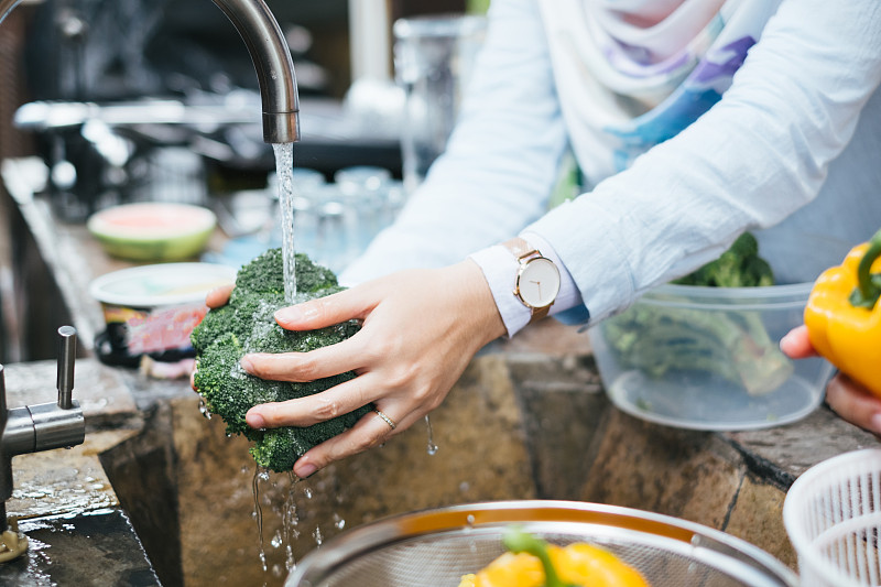 家庭厨房中正在清洗西兰花的场景