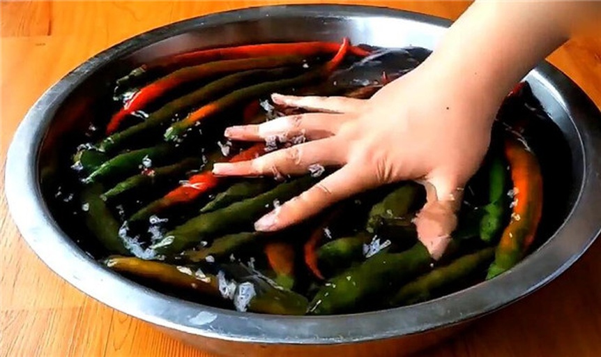 一个白色陶瓷洗手池边缘放着一盒牛奶和一瓶透明装的食用油,旁边有一条蓝色毛巾,用于处理切辣椒后的清洁用品展示 厨房洗手池边放置牛奶盒与食用油瓶