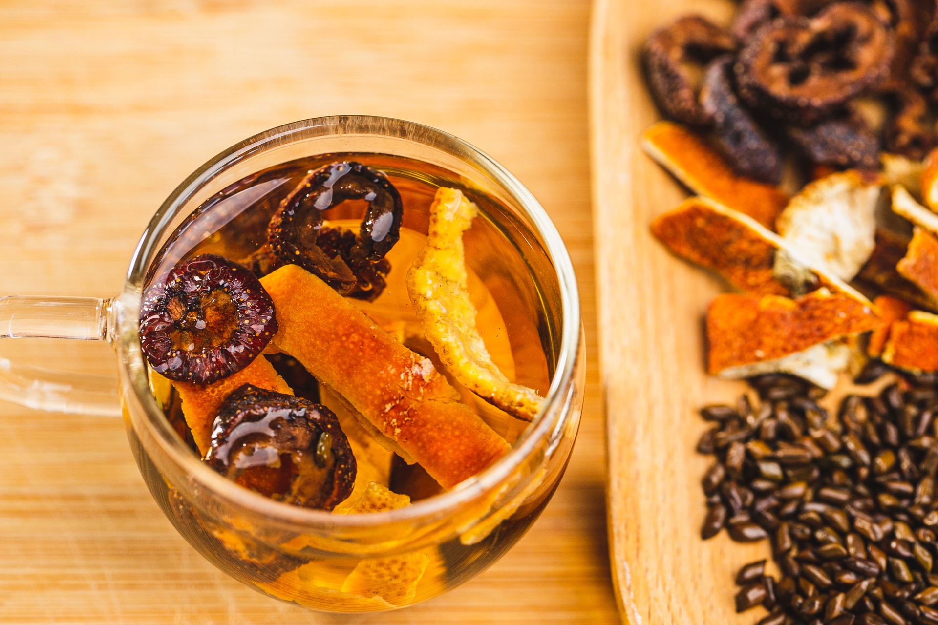 一个木质托盘上摆放着晒干的柚子叶、玻璃瓶装的柚子叶精油、一锅正在煮沸的柚子叶水,旁边配有毛巾和足浴盆,展现柚子叶在居家养生中的多种用途 柚子叶用于生活场景