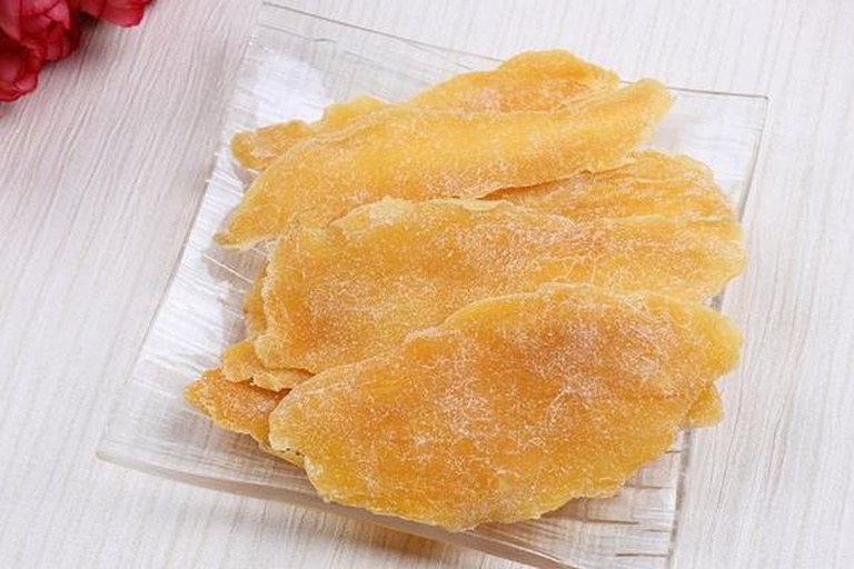 玻璃罐中装满金黄色芒果干置于厨房台面