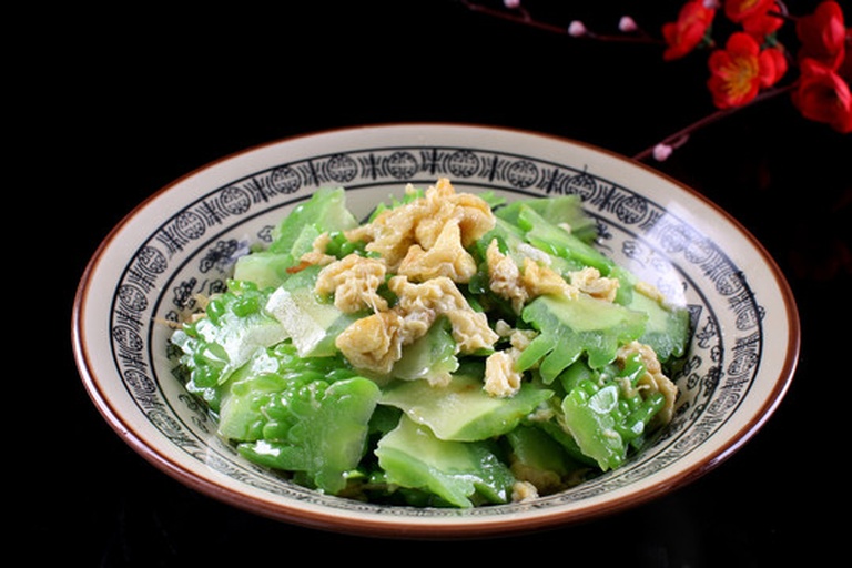 高清俯拍:左侧为新鲜青绿带白霜苦瓜(长约25cm,瘤粒凸起分明),右侧为4枚散养土鸡蛋(蛋壳浅褐,表面有天然气孔纹理),中间铺陈洁净竹砧板与不锈钢刀具,背景虚化突出食材本真质感 苦瓜与鸡蛋原料特写