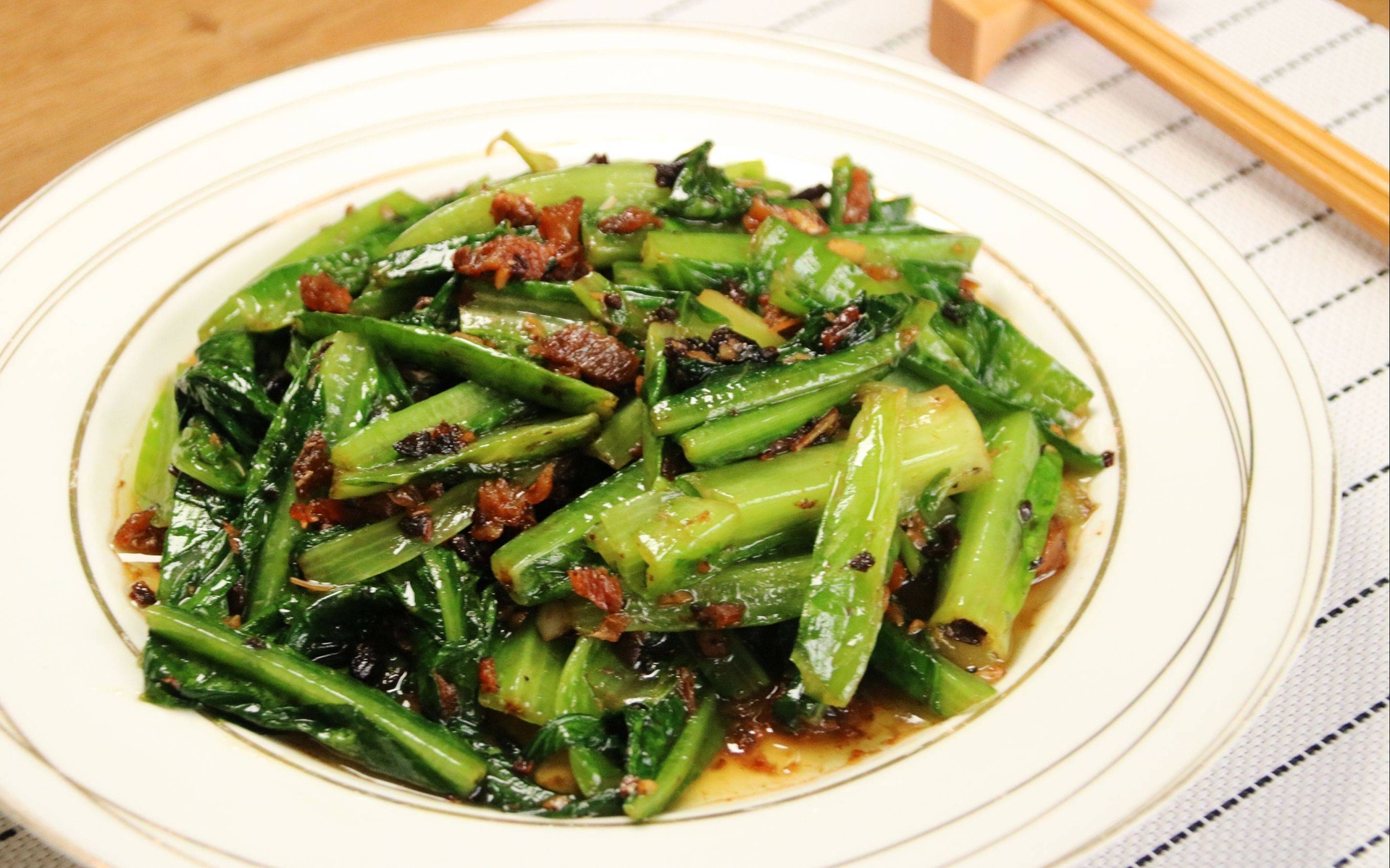 白色瓷盘中盛放着刚出锅的蚝油白菜,菜色翠绿黄心分明,表面泛着晶莹油光,酱汁浓稠适中,部分附着在菜叶上,旁边点缀有少许蒜末,整体呈现餐厅级摆盘效果 蚝油白菜出锅装盘场景