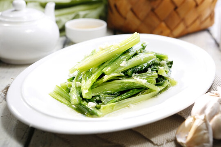 一张温馨的家庭餐桌场景,盘中盛有一道清炒油麦菜,色泽碧绿油亮,搭配米饭和一碗汤,背景模糊显示一家人正在用餐 家庭餐桌上的油麦菜菜肴