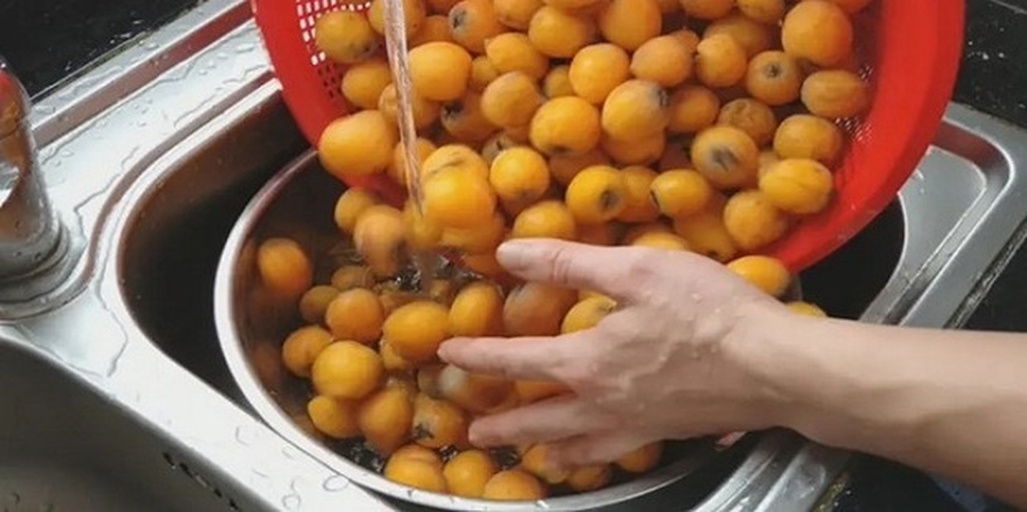 家庭成员在厨房清洗枇杷准备食用场景