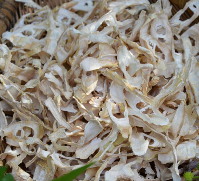 山竹干特写：琥珀色半透明果肉片平铺于白瓷盘，表面微泛油润光泽，边缘略卷曲，可见细微果肉纤维纹理