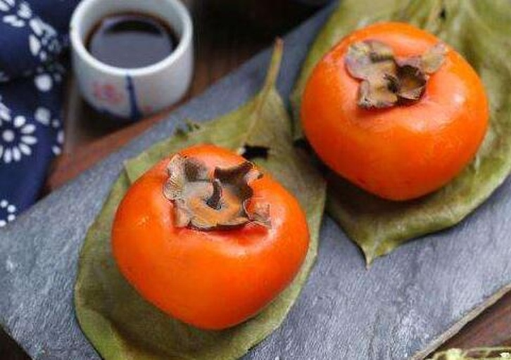 原创IP插画:‘柿孑’拟人化视觉形象设计,融合食物属性、秋日元素与轻盈治愈感,用于品牌年轻化传播场景 手绘风格插画:Q版“柿孑”IP形象——拟人化脆柿顶着绿萼小帽,圆脸带笑,手持银叉叉起一块晶莹果肉,周围环绕枫叶、露珠、蜂蜜罐与简约线条秤砣,整体色调为暖橙、苔绿与奶油白