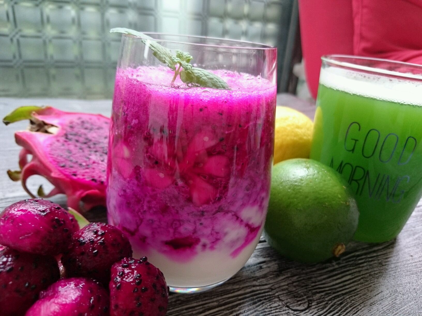 火龙果椰青水果汁户外饮用场景图,展现清凉夏日风格与自然氛围 一位女性手持透明水杯,杯中为粉白色火龙果椰子水混合果汁,背景为沙滩与棕榈树,阳光明媚