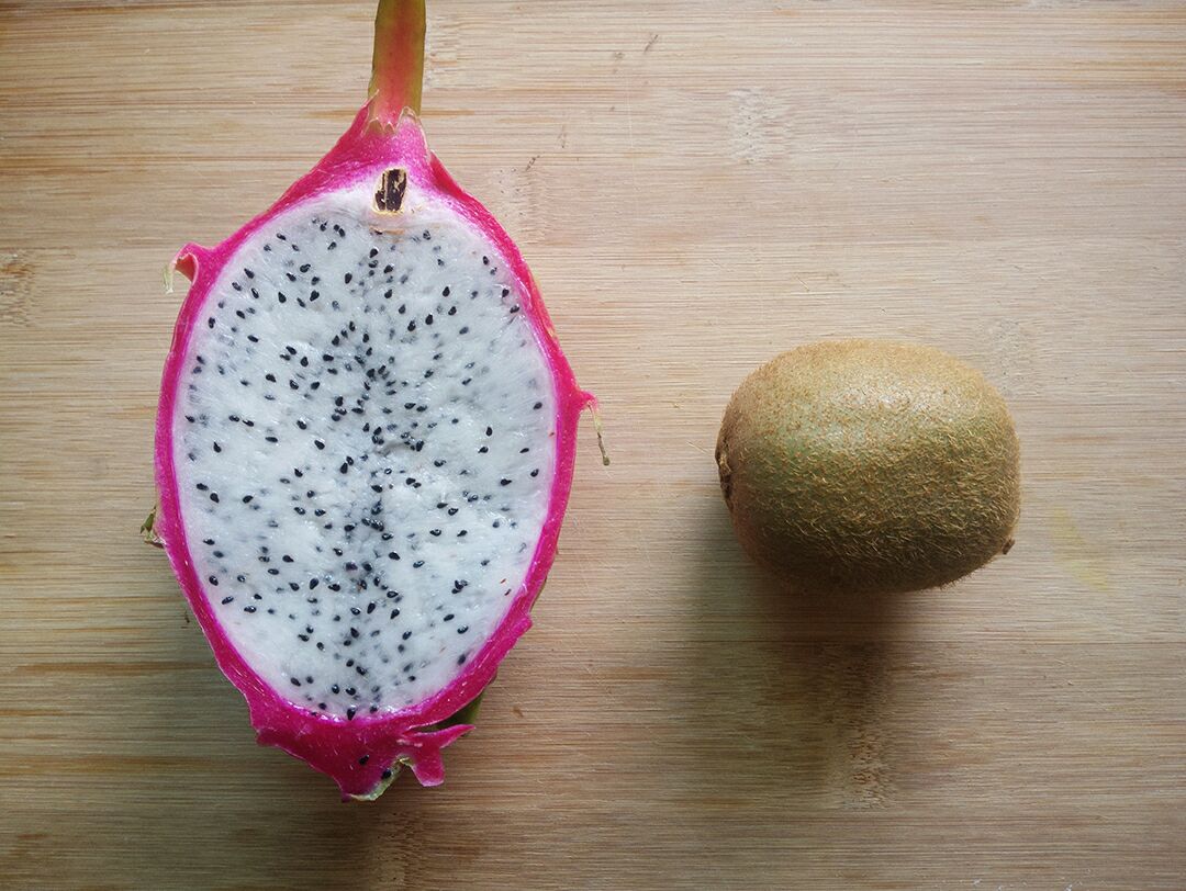 左侧砧板上有明显紫红色火龙果汁液残留,右侧同一砧板经清洁后恢复原色,旁边放置柠檬片、小刷子和清洁布,展示清洁工具组合 厨房台面与砧板上火龙果残留汁液清洗对比图