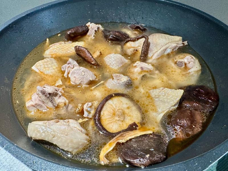 炖煮中的香菇鸡腿，汤汁浓郁，香气四溢