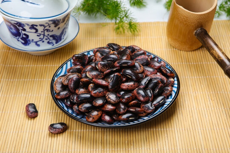 场景图:一口陶瓷砂锅置于电磁炉上,锅内清水翻滚,可见数颗黑豆与白色浮小麦漂浮其中,蒸汽袅袅上升;旁边放置玻璃杯盛有已煮好的深褐色茶汤,色泽清亮,背景为简约中式厨房环境 黑豆浮小麦煮水过程展示