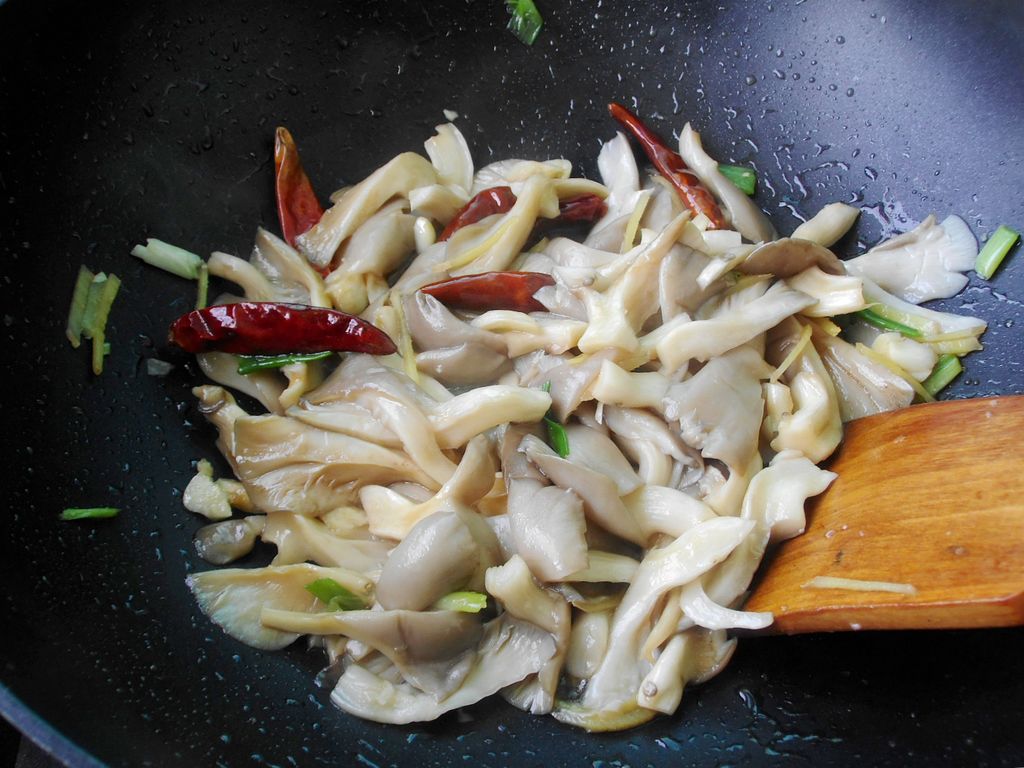 家庭厨房中正在翻炒平菇的场景