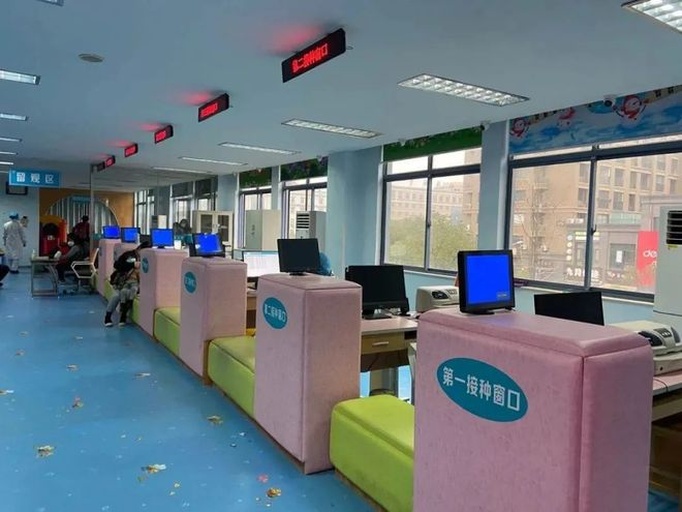 一位年轻的母亲抱着约6岁的小女孩站在社区卫生服务中心的诊室门口,正在向穿白大褂的女医生咨询问题,桌上摆放着听诊器和病历本,墙上挂有‘儿童保健’标识牌,体现家庭健康咨询的真实场景 一位年轻母亲抱着小女孩咨询医生