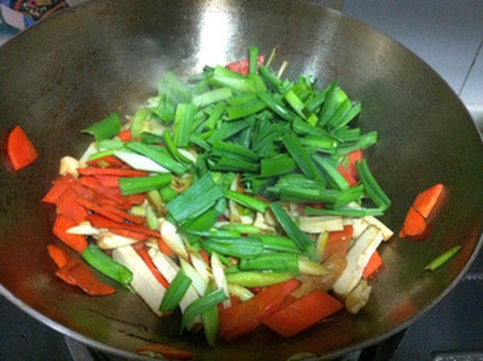 一锅正在炖煮的芸豆胡萝卜炖菜，锅中可见绿色芸豆段与橙色胡萝卜块混合，汤汁微沸，旁边配有切好的鸡肉丁和调味料
