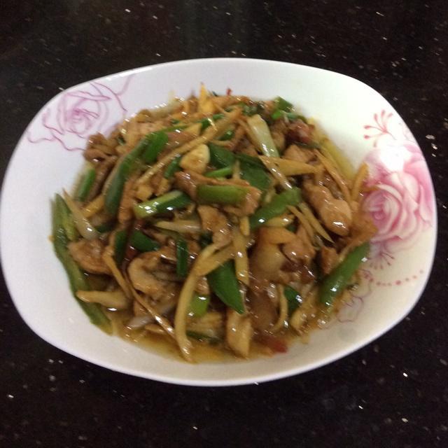 一盘色彩鲜艳的青红椒炒肉片,红椒呈亮红色,青椒翠绿,肉片褐黄分明,整道菜摆放在白色瓷盘中,表面泛着微微油光,旁边配有米饭一碗 青红椒炒肉片成品图