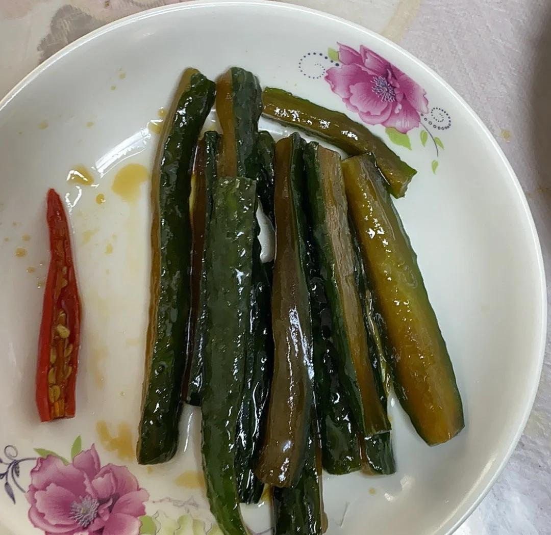 一盘装好的虾油小黄瓜,色泽翠绿,虾油微微泛红,蒜末与辣椒点缀其中,盘边有少许油光 虾油小黄瓜装盘图