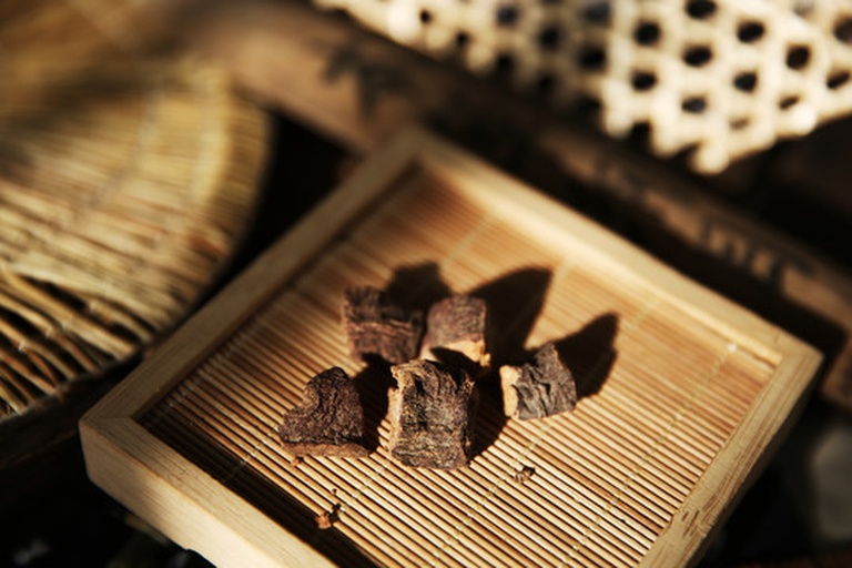 静物摄影风格图片,前景是一个透明圆形玻璃密封罐,内盛金黄色夹杂褐色参片的炒米,旁边摆放一把原木色短柄勺,右侧是一杯清澈淡金色液体(冲泡后的炒米茶),背景为米白色亚麻桌布,整体氛围温暖宁静 成品高丽参炒米装在透明玻璃罐中,旁边配有陶瓷勺和一杯冲泡后的淡金色饮品