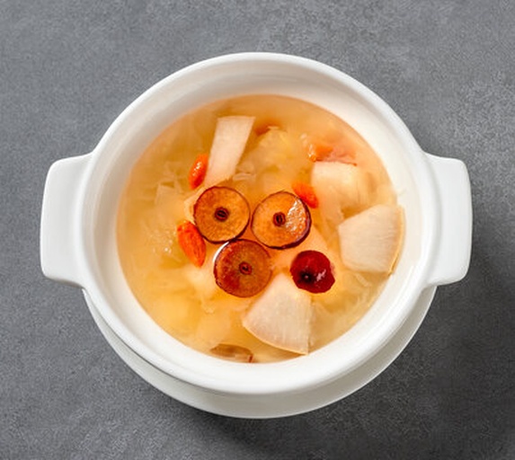 一碗热气腾腾的白术红枣粥,旁边摆放着白术片和红枣、枸杞等食材 白术养生食谱示意图