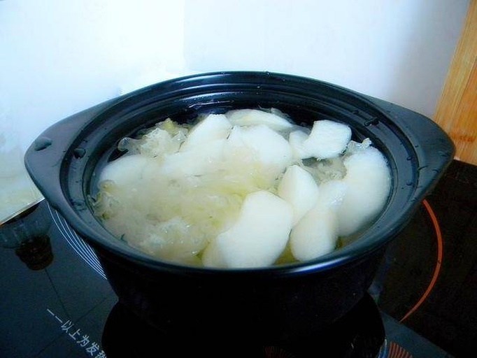 炖锅中银耳与雪梨、莲子正在慢炖,汤色渐浓 炖煮中的雪梨银耳莲子羹