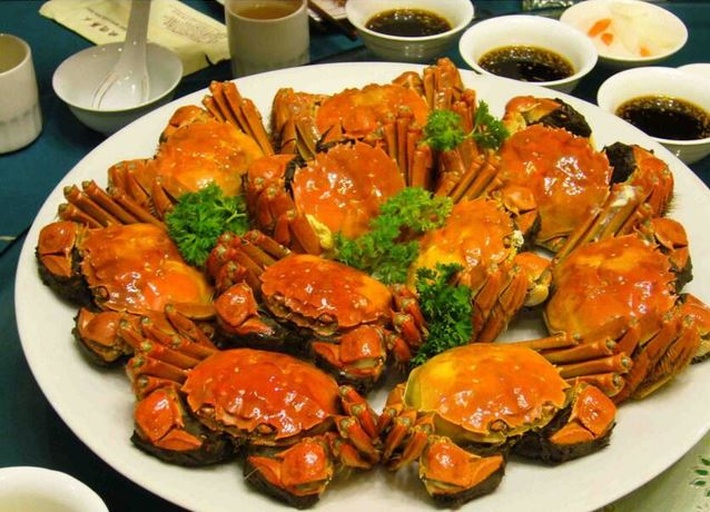 家庭聚餐场景中的大闸蟹宴,展示中国人对时令美食的情感连接与文化传承 一家人围坐在餐桌前开心地享用清蒸大闸蟹,桌上摆满蟹具、姜茶和果盘,灯光温馨,充满节日团聚气氛