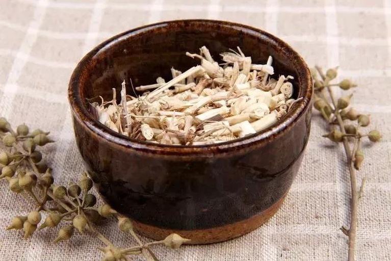 一个陶瓷锅中正在熬煮深绿色的侧柏叶药材,水面漂浮着完整的叶片,旁边放置干燥的侧柏叶药材包和木质搅拌勺,背景为传统中药房木质柜子 侧柏叶煎煮过程