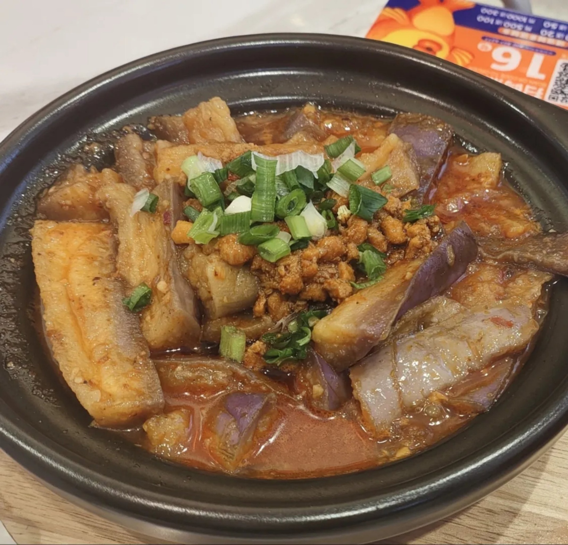高清俯拍:深褐色砂煲中盛满油润亮泽的线茄煲,茄段完整饱满、酱汁浓稠如琉璃包裹,可见隐约的香菇丁、肉粒及青红椒丁,表面撒少许葱花,热气氤氲,砂煲边缘有琥珀色酱汁挂壁 线茄煲成品特写