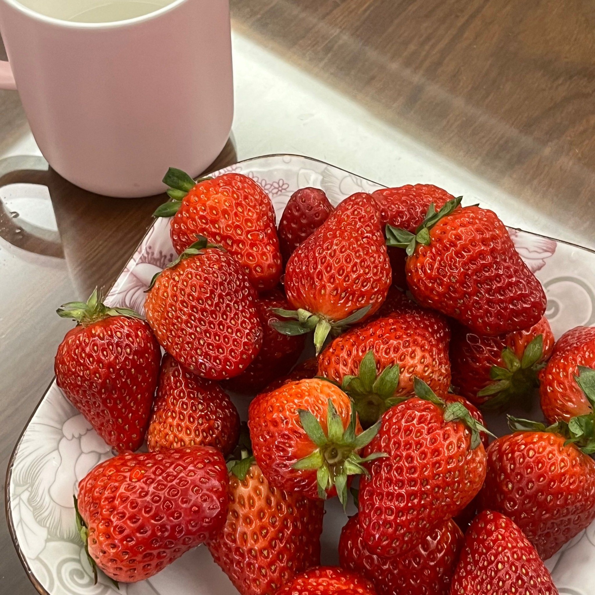 一杯粉红色的草莓牛奶,杯口装饰有新鲜草莓片和薄荷叶 草莓牛奶成品图
