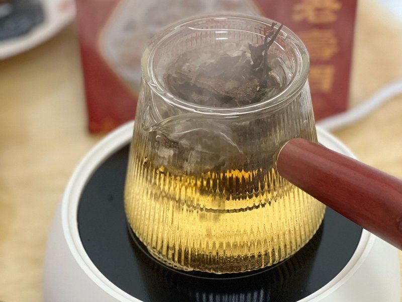 展示茶具预热步骤,玻璃茶壶中倒入热水,背景为厨房环境 金丝皇菊泡茶步骤图 - 茶具预热