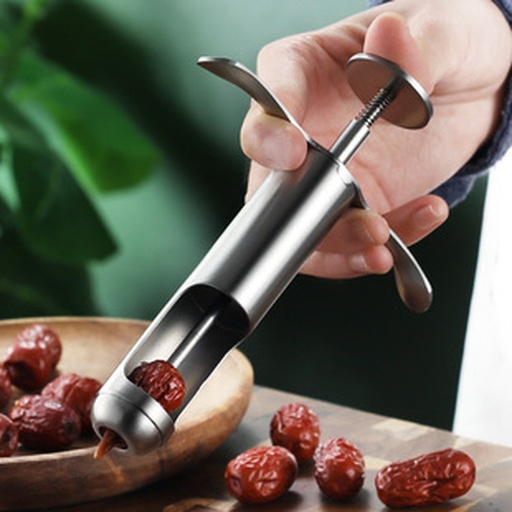一名厨师正在使用不锈钢红枣去核器处理干燥红枣,桌上摆放着带核红枣、已去核红枣和收集的枣核,工具清晰可见,场景为明亮厨房环境 红枣去核工具与操作示意图