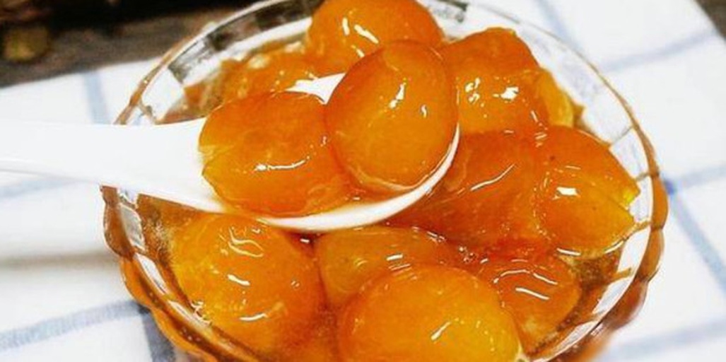 玻璃碗中盛放着正在糖浆中熬煮的金黄色橙皮条,锅具为不锈钢小奶锅,旁边摆放着新鲜橙子、糖罐和柠檬,展示从原料到半成品的转化过程,光线柔和,突出食材自然质感 金堂脐橙皮蜜饯制作过程