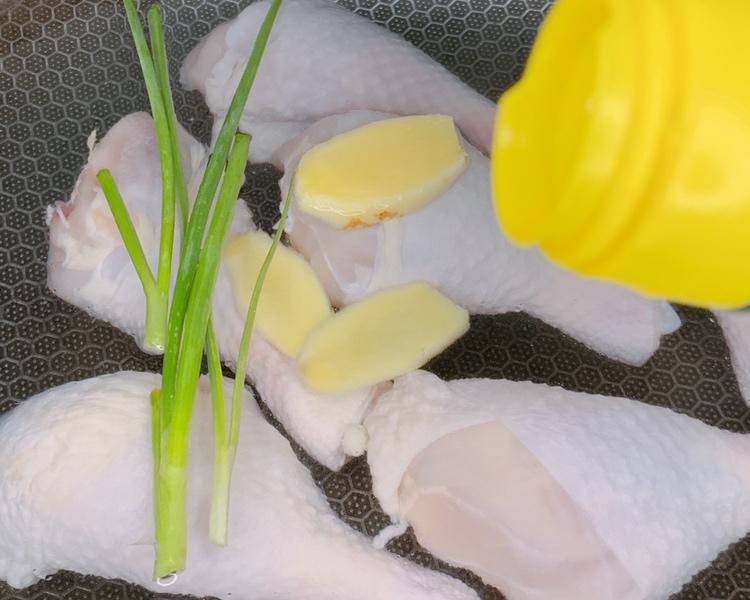 一位厨师正在灶台前操作,锅中鸡腿与大葱正在翻炒,酱汁微沸,手持木铲,背景有酱油瓶、葱段、蒜瓣等调料,展示葱烧鸡腿的制作过程 厨房烹饪过程图