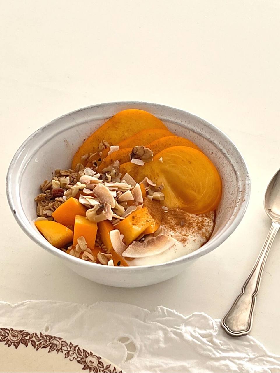 一张餐桌上的健康搭配图:左侧是一盘切好的脆柿块,右侧配有酸奶、坚果和全麦面包,旁边有一杯温水,整体呈现科学合理的加餐组合,背景为明亮厨房 脆柿与健康饮食搭配场景