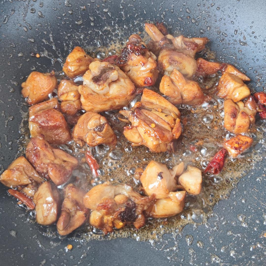 锅中正在翻炒的香辣小鸡腿,鸡肉与大葱、辣椒混合,色泽红亮,香气四溢 香辣小鸡腿翻炒过程