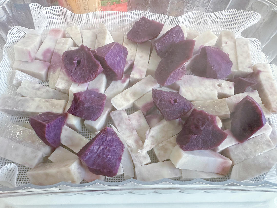 一锅正在蒸制的紫色香芋块,热气腾腾,芋头表面微微湿润,部分已裂开露出内部紫红色的肉质;锅具为不锈钢蒸锅,背景模糊 正在蒸煮的香芋块特写