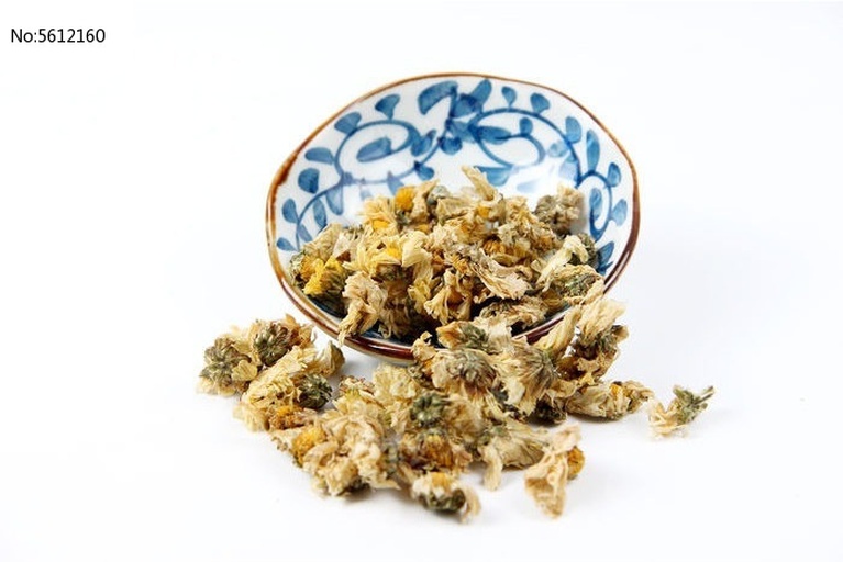玻璃杯中正在冲泡野菊花茶,热水倒入后花朵缓缓舒展,水中呈现淡黄色,几朵完整的野菊花漂浮于水面,背景为木质茶桌,旁边放置陶瓷茶壶与茶匙,展现传统养生饮茶场景 野菊花茶冲泡过程