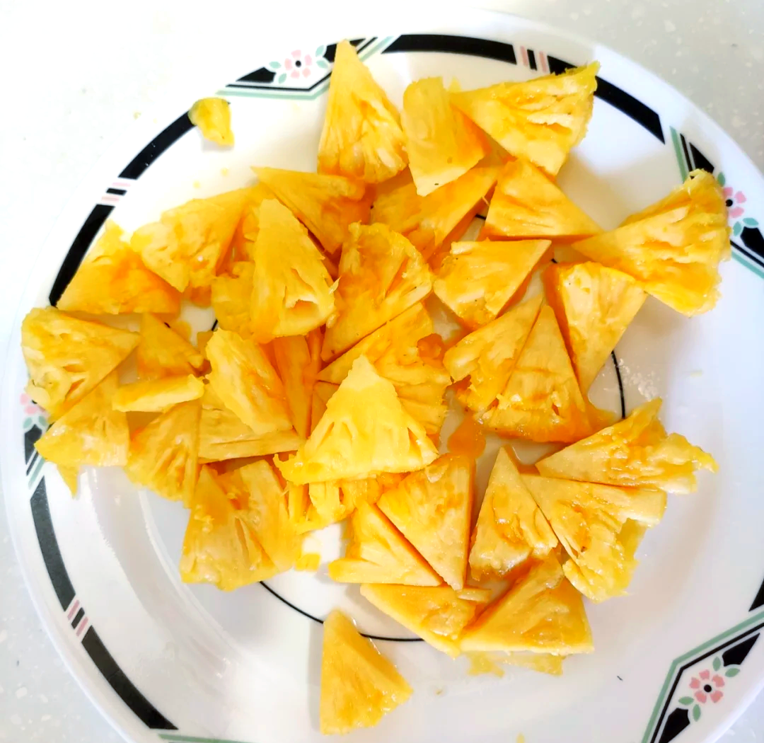 一家三口坐在阳台餐桌旁,桌上摆放着一盘切好的新鲜菠萝块,孩子正开心地用叉子取食,阳光洒在果盘上,氛围温馨自然 家庭享用新鲜菠萝场景