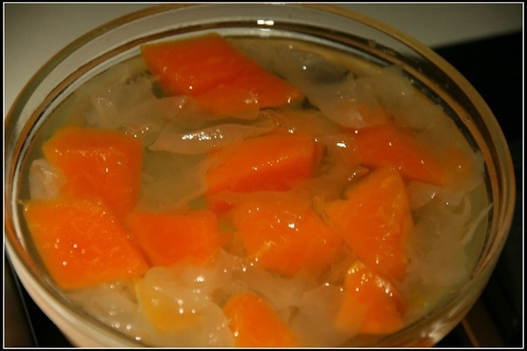 三组食材分开放置在白色陶瓷盘中:左侧为一朵完整的干制椴木银耳,耳片厚实呈浅琥珀色;中间为新鲜剥好的百合瓣,洁白饱满;右侧为切块的橙黄色木瓜,果肉细腻多汁。背景为原木砧板,整体呈现自然健康风格 食材摆盘图