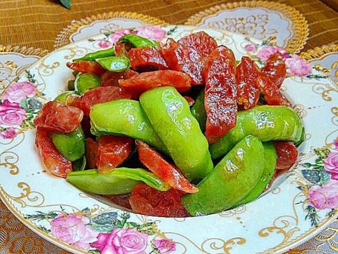 高清微距图:左侧为新鲜翠绿带蜡质光泽的嫩扁豆角(长度约13cm),右侧为切片后经温水浸泡并吸干水分的广式腊肠薄片(肥瘦纹理清晰,表面干燥无油光) 扁豆角与腊肠原料特写