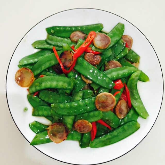 成品青豌豆炖肥肠特写，肥肠油亮红润，青豌豆碧绿完整，汤汁浓而不稠，整体色泽诱人