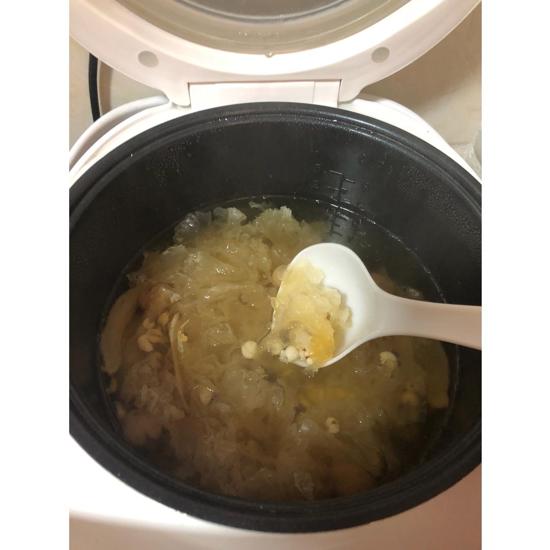 砂锅中正在炖煮的银耳羹,液体呈乳白色微稠状,银耳耳片舒展半透明,表面有细密气泡缓慢上升。锅边放置一个计时器,显示时间为‘01:30’,体现慢炖过程 炖煮过程特写